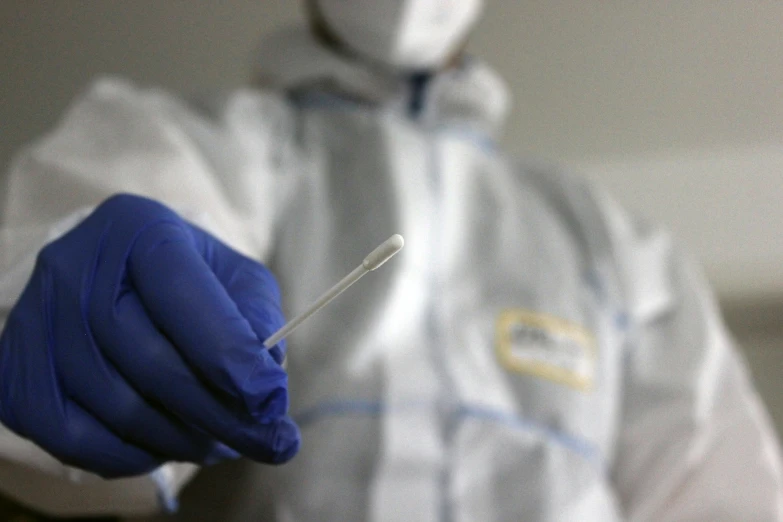 a person in medical gear holding up a medical tool