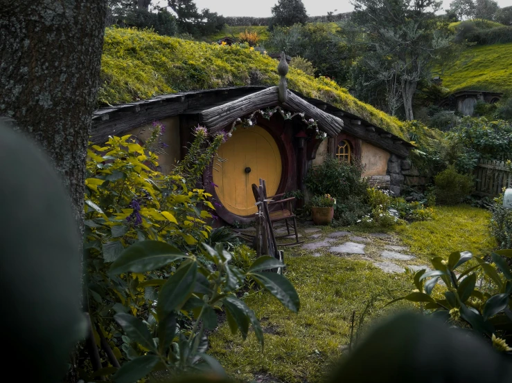 a green roof and thatched roof house next to a tree