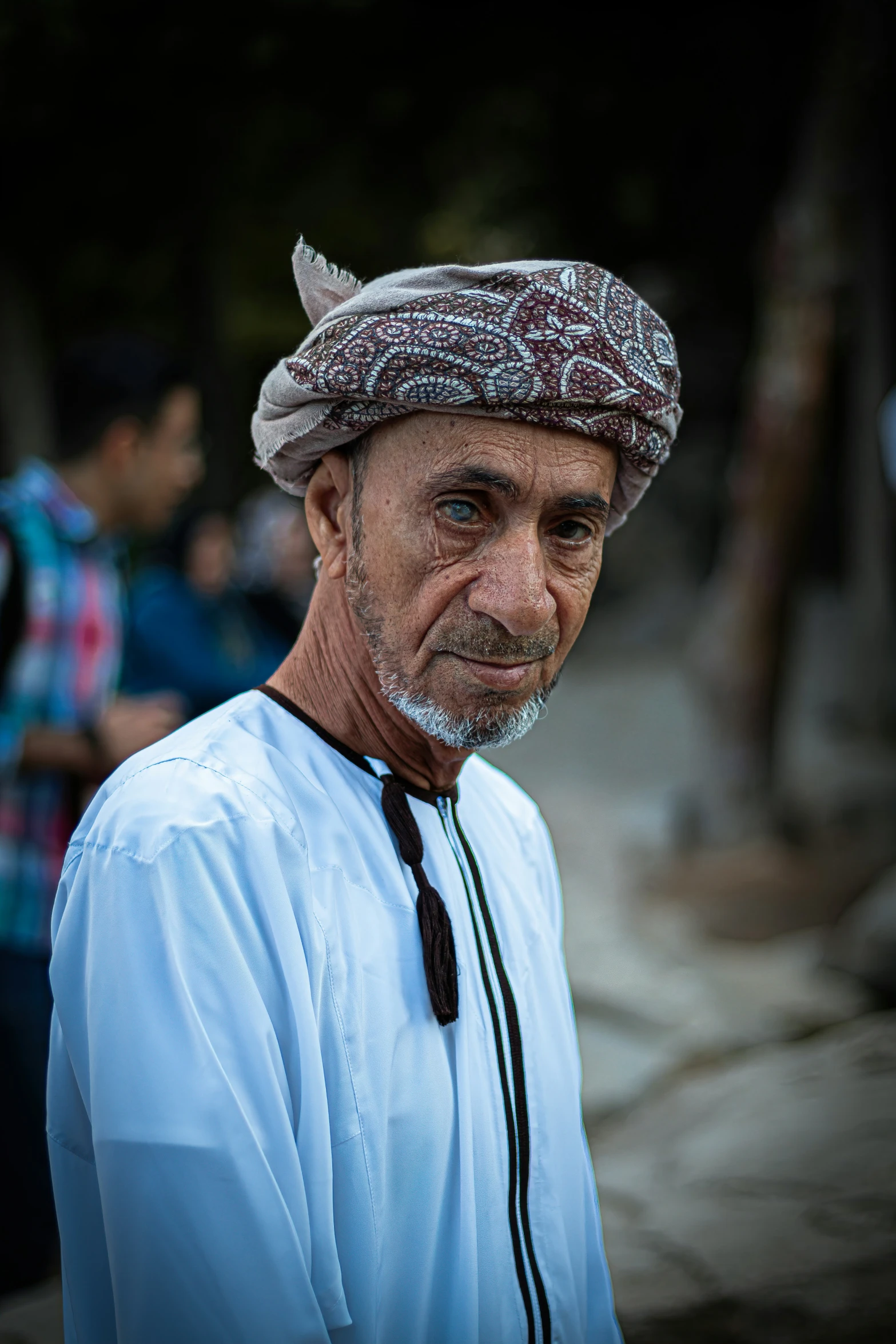 man with greying hair and cap and white shirt standing outside