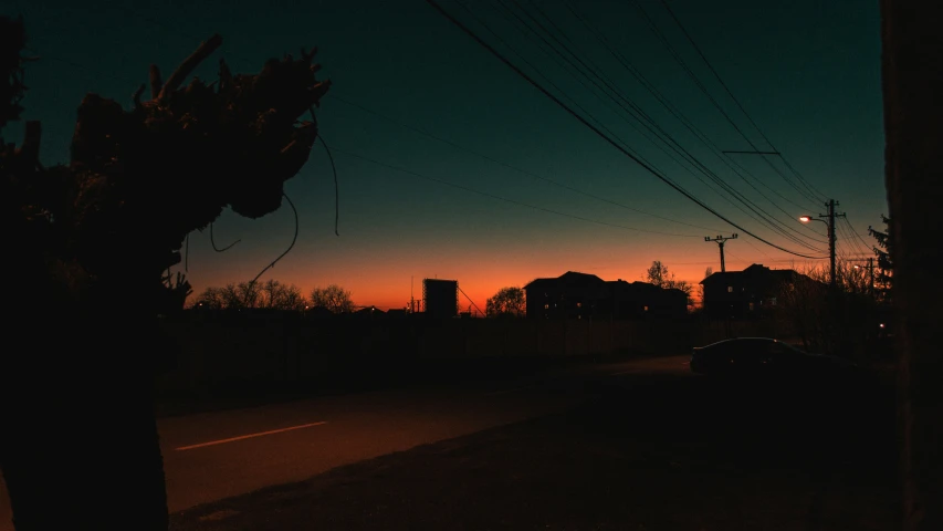 the silhouette of a car on the street with power lines