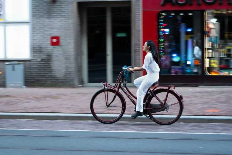 a woman in a white suit rides her bicycle on a city street