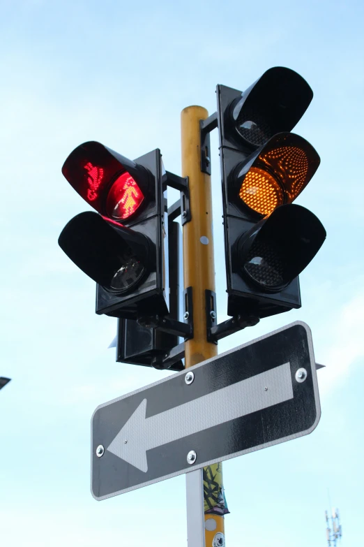 two traffic lights on a wooden pole next to a sign