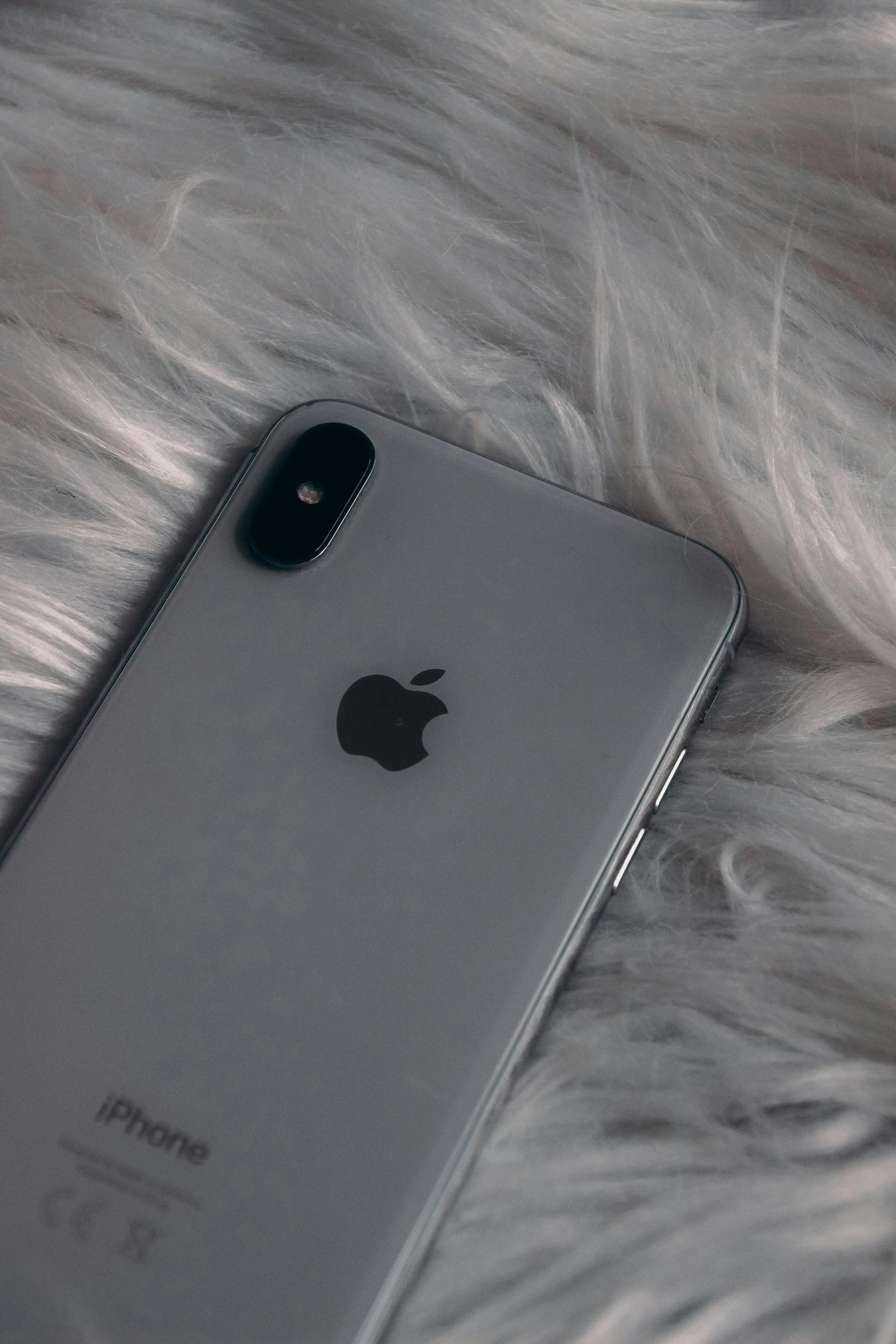 an iphone is laying on some silver fur