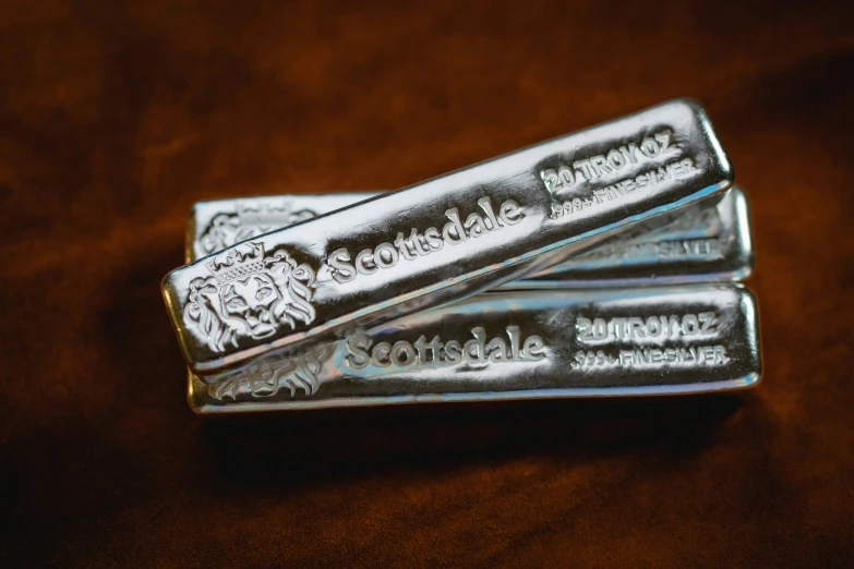 three silver bars sitting on top of a brown table