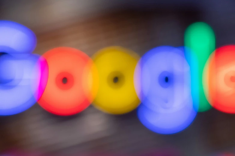 blurry pograph of the word google illuminated with neon colors