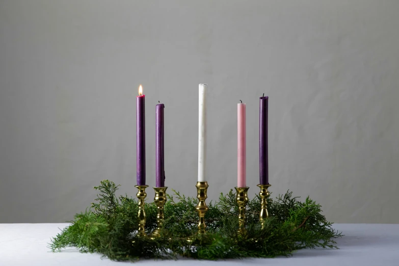 three candles and greenery on a white surface