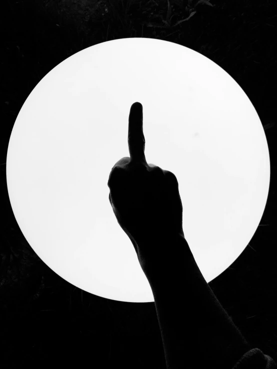 a person holding up a thumb against a white circle