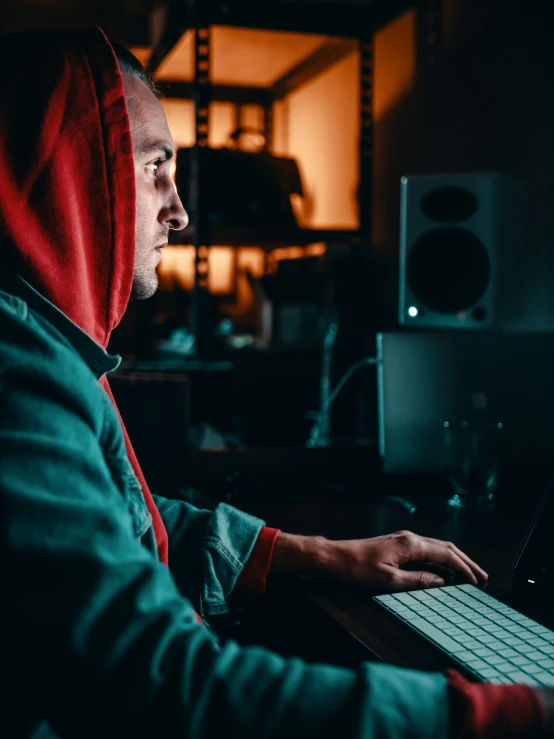 a man wearing red hoody working on his laptop