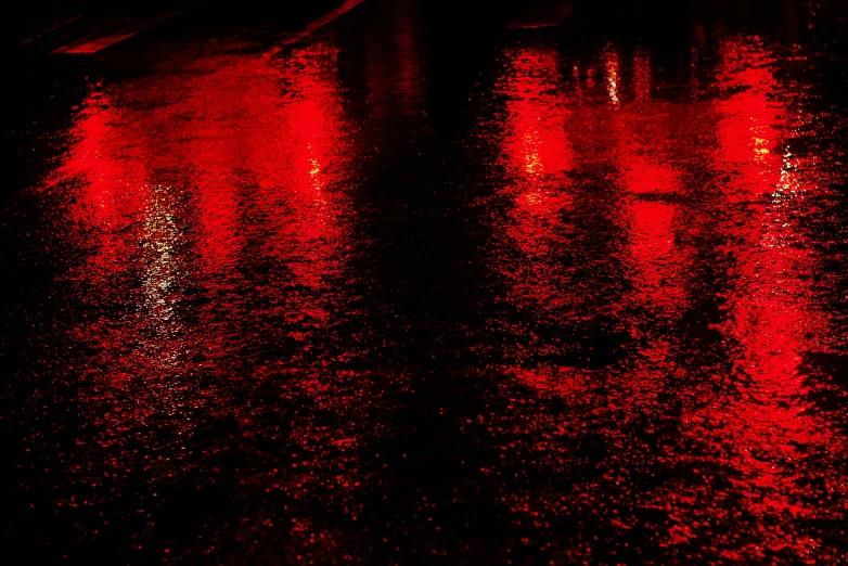 the rain drops on the water while lights shine in the background