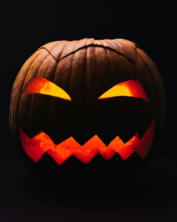 an orange lit jack o lantern on a black background