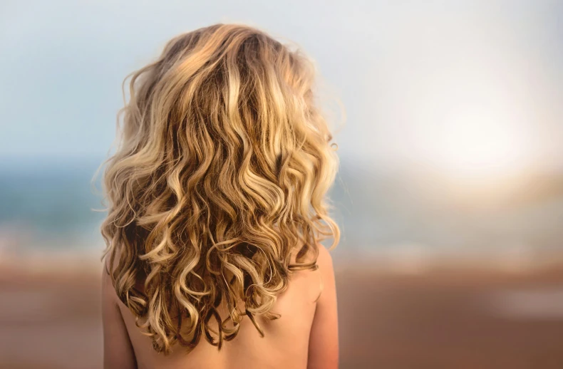 a woman standing at the beach looking out to sea