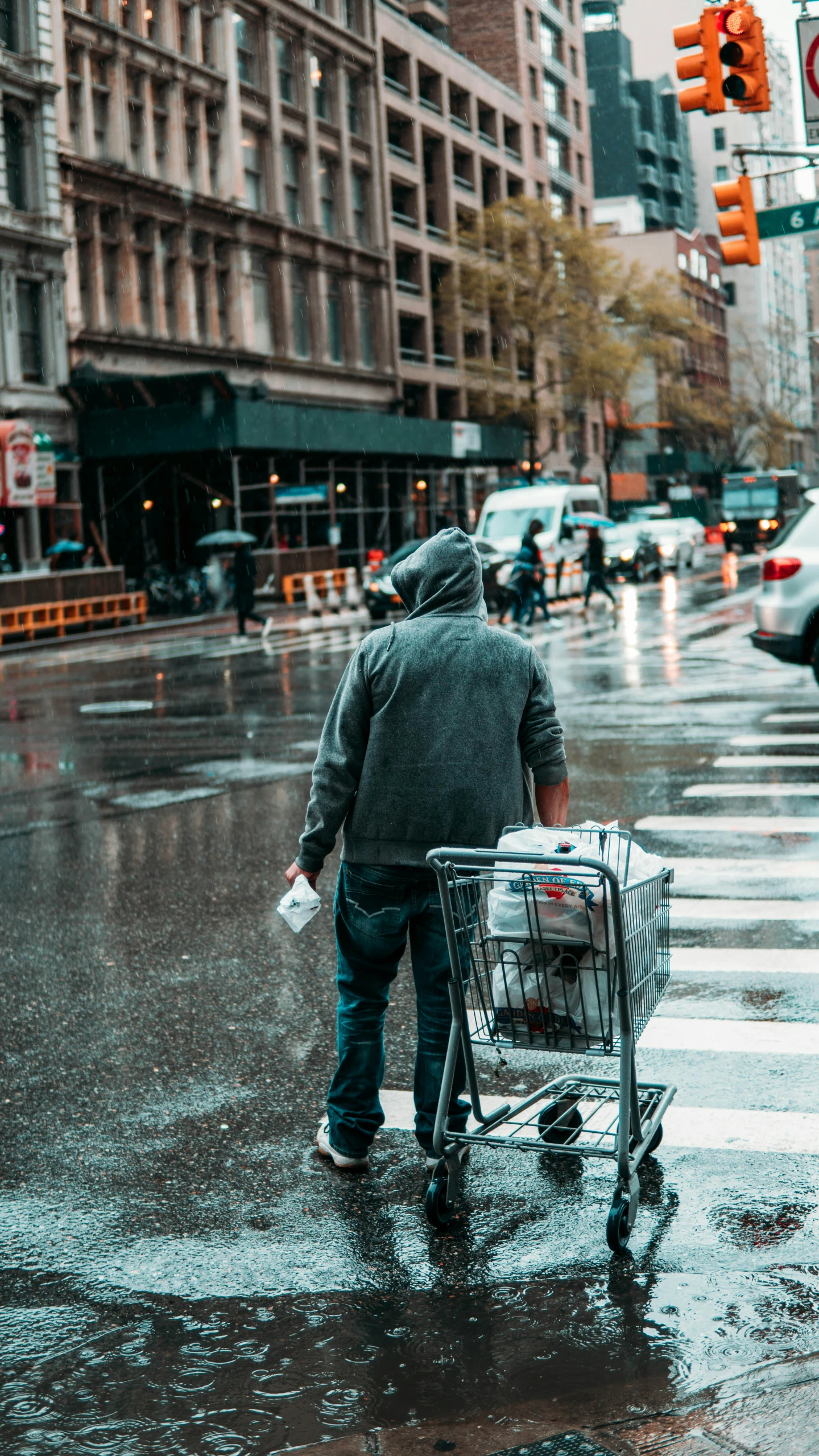 a person with a shopping cart crosses the street