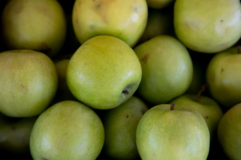 a close up of some green apples in a pile