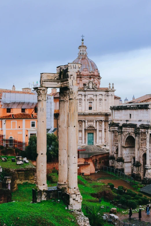 ruins with people walking around it next to a building