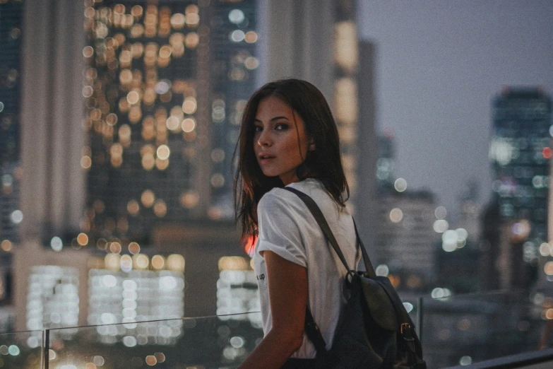 a woman stands on a ledge above the city lights