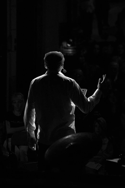 a man with his arms outstretched is talking in front of an audience