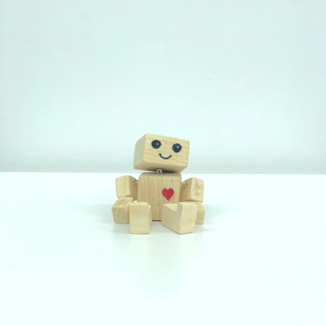 a wooden toy sitting on a white table with one foot in the air