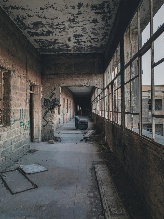 an abandoned, derelict building has large windows and graffiti on the walls