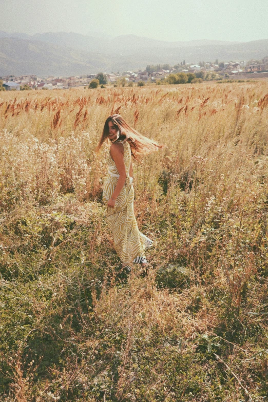 a woman wearing a yellow dress is in the grass