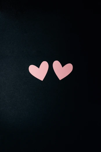 two hearts are on the back of a black surface