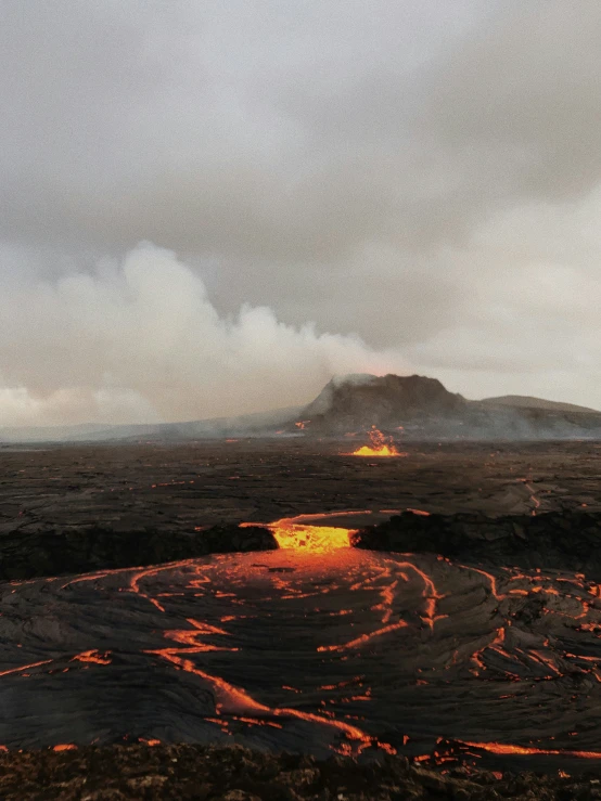 a lava flow in front of a dark, cloudy sky