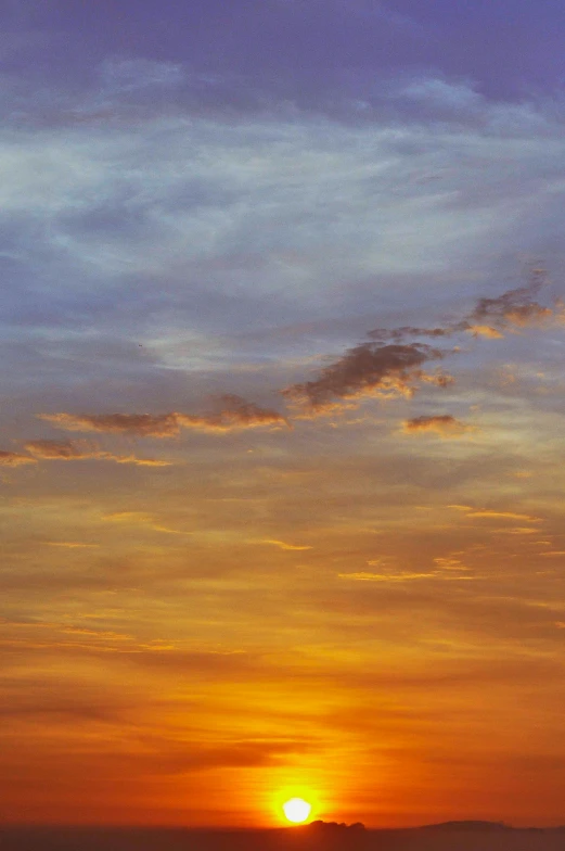 people ride on the beach as the sun sets