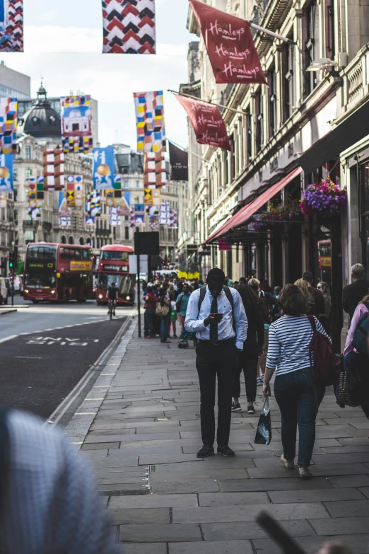 a group of people walking down a city street next to tall buildings