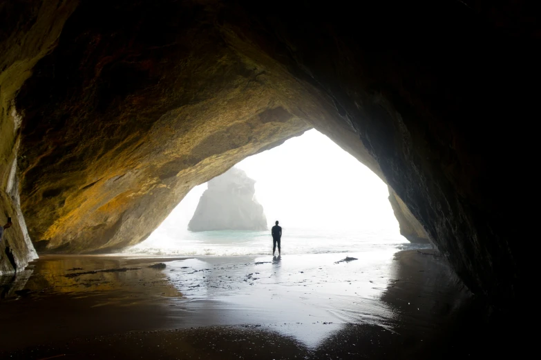 a person standing inside of a cave on a beach