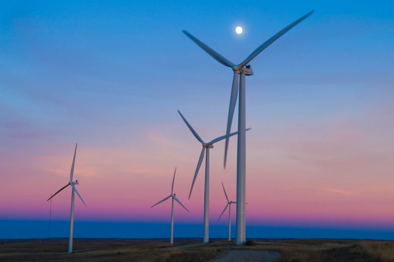 a wind farm with multiple turbines in the evening sky