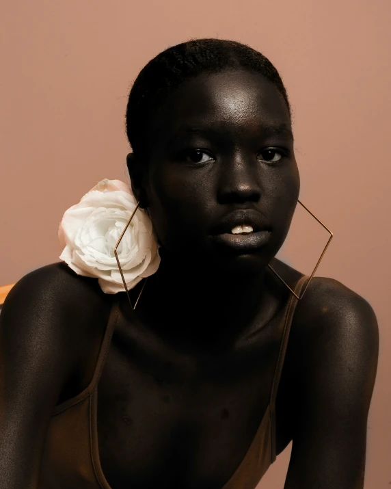 a young black woman with dark skin wearing a white flower