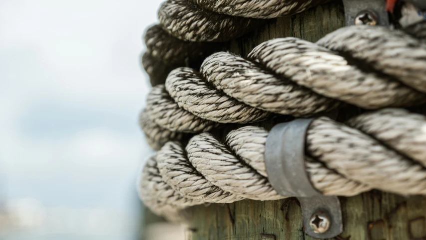 the rope of an old wooden pole is covered with white and black ropes