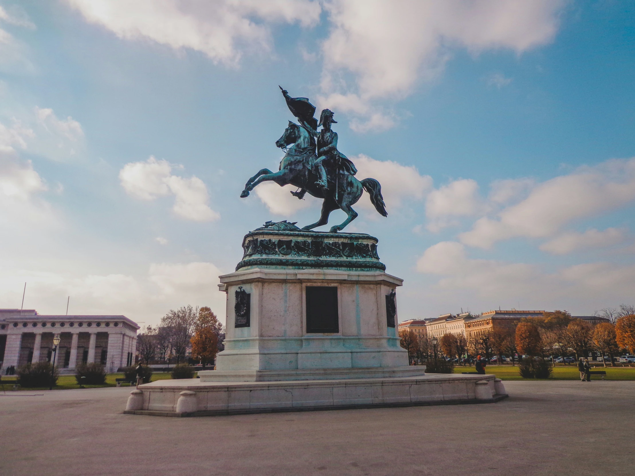 a statue in a park that has clouds in the sky