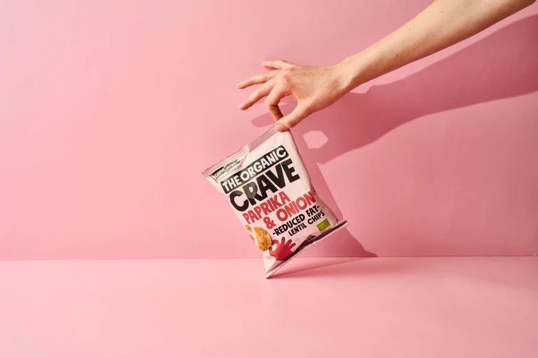 a hand reaching into a bag of candy on a pink surface