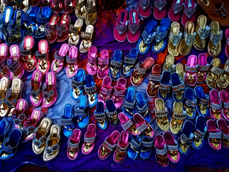 many pairs of bright colored shoes are laid out for sale