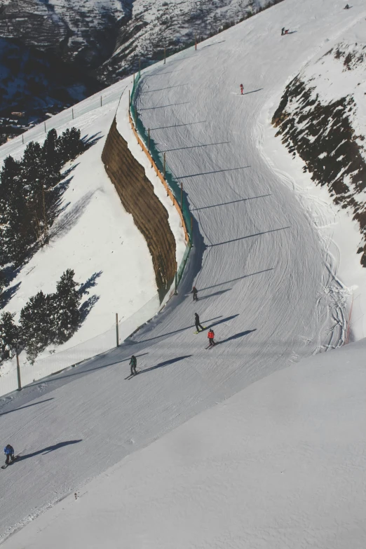 people skiing up a snowy slope with trees on the side