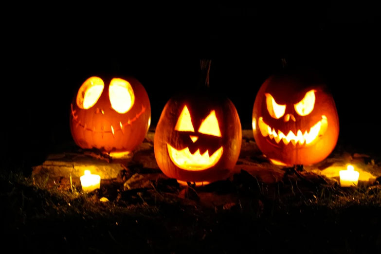 a bunch of pumpkins lit up by candles