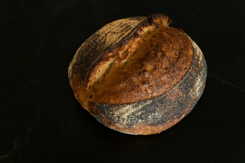 a round loaf of bread is pictured on a black surface