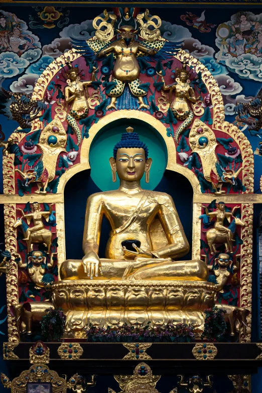 a gold buddha statue next to the wall with designs on it