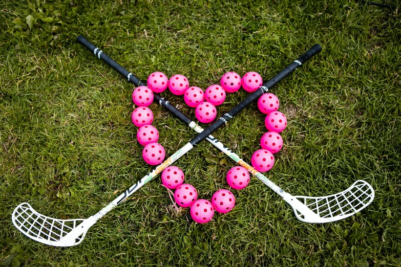 the heart shaped item is made of pink balls and lacrosse sticks