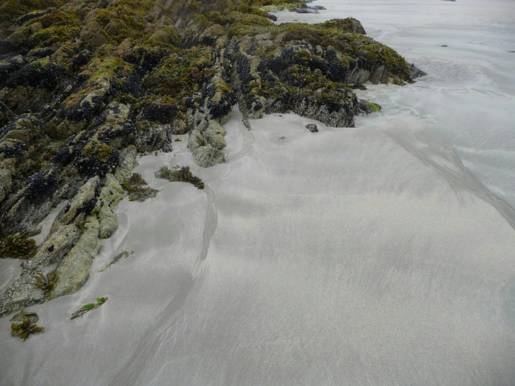 an ocean with some rock and sand near water