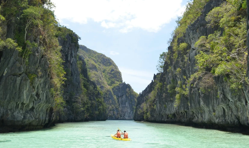 people are in a boat on the water between mountains