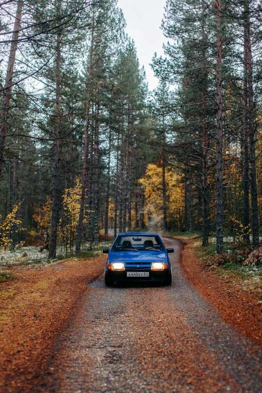 a car sitting on a dirt road near many trees