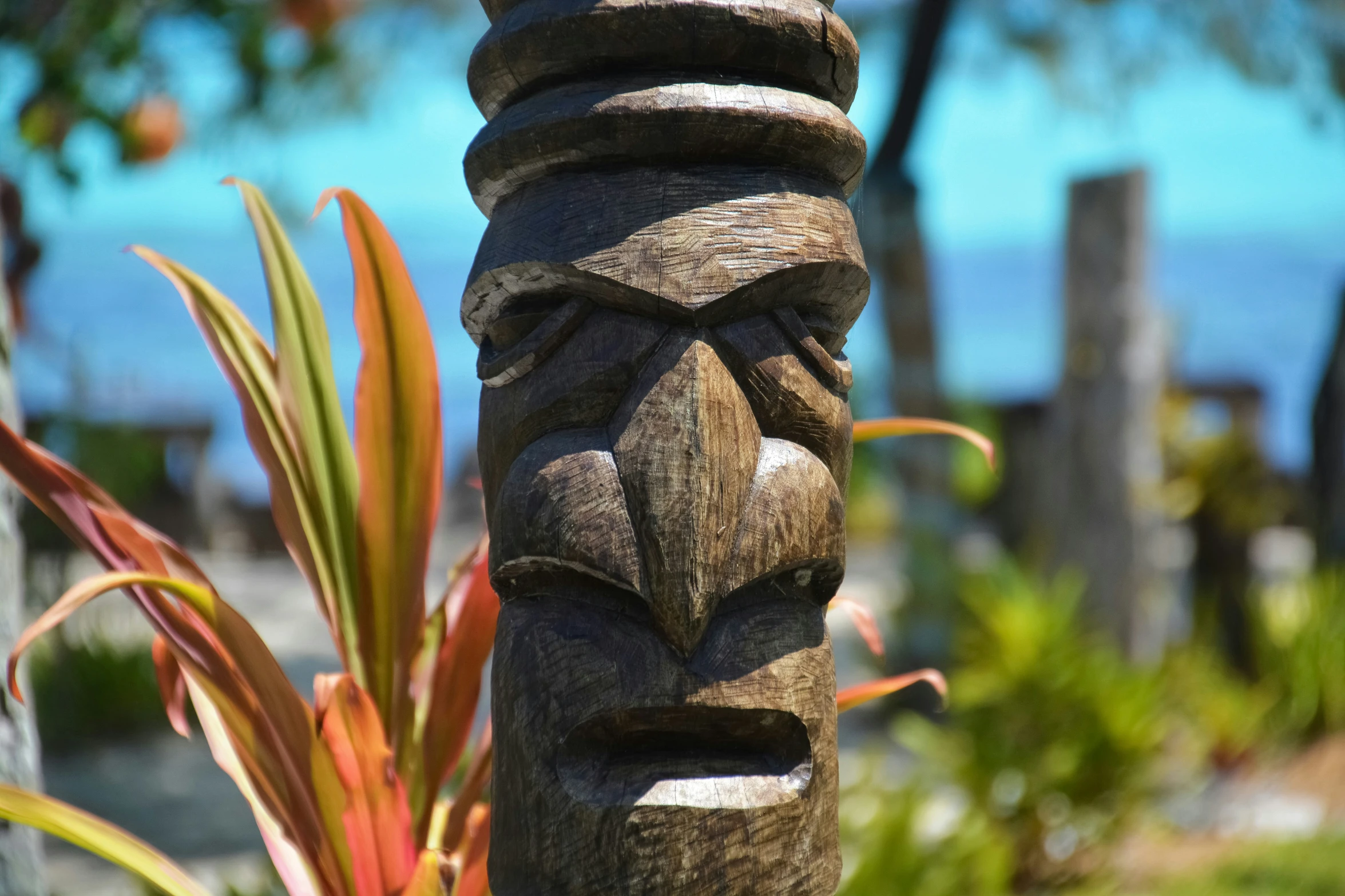 a tiki standing next to a potted plant near a fence