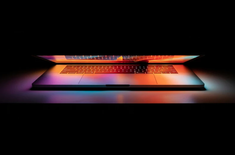a laptop in dark with a neon colored surface