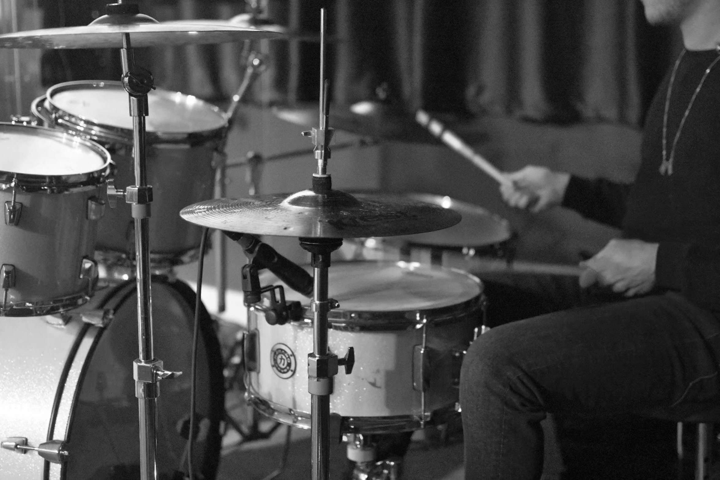 a man sits in front of two drums in black and white