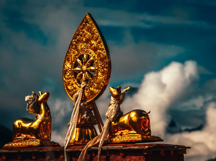 three golden lions statues in front of the clouds