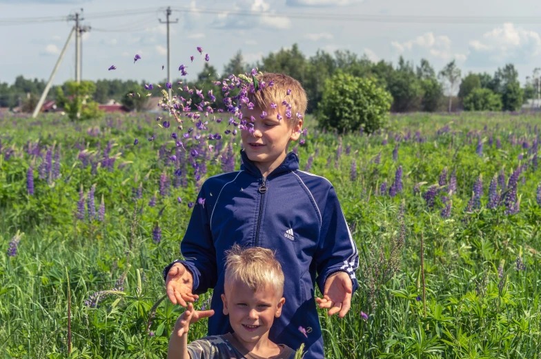 two children with flowers in their hands standing in the grass