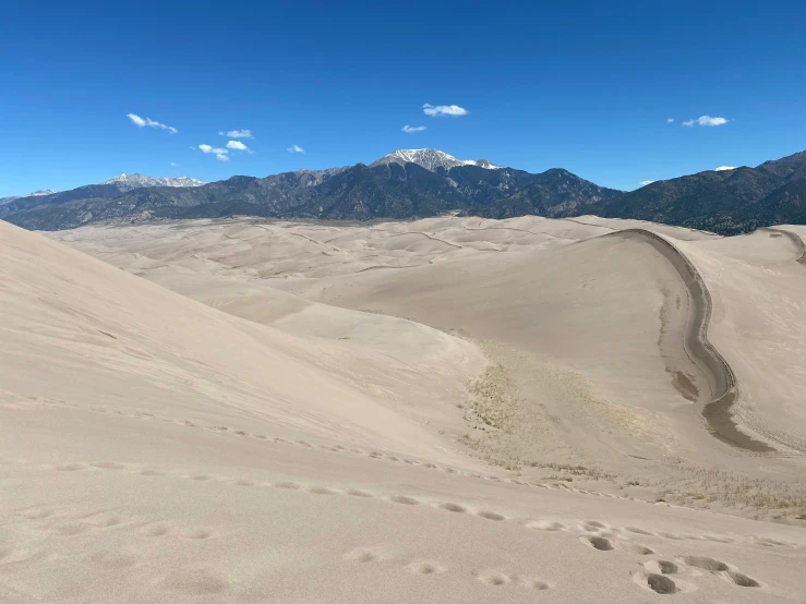 the view of sand hills and mountains from the top of a hill