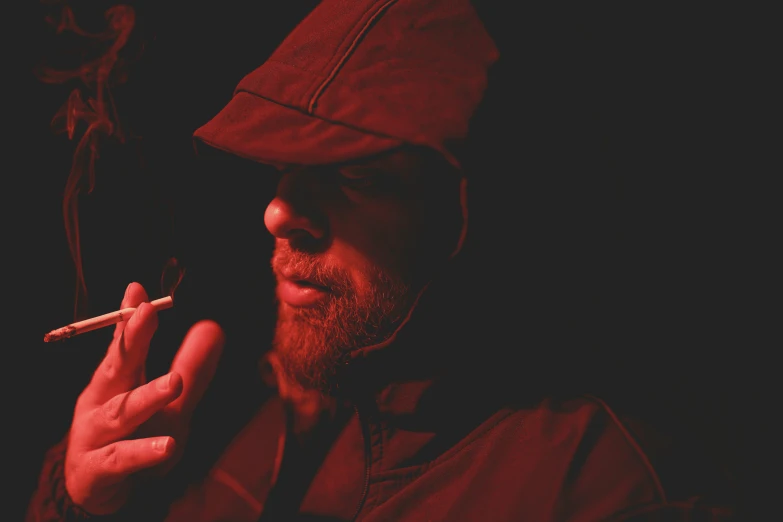 a bearded man is smoking a cigarette on a black background