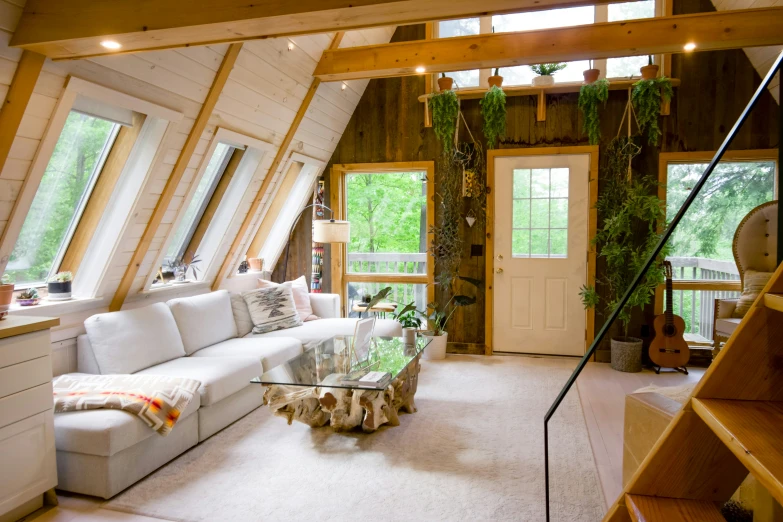 a loft with a lot of windows, white couches and a glass table in the corner